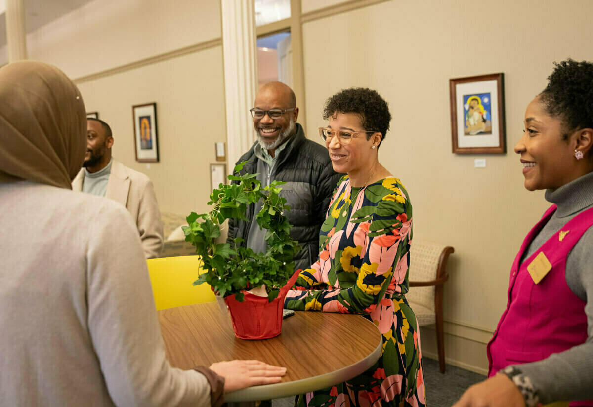 An african american couple smile as they meet with people at an Office of Institutional Transformation open house