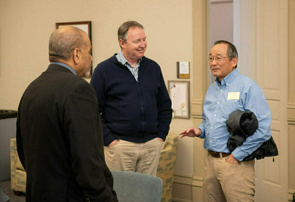Rev. Hugh Page speaks with faculty memebers at an An african american couple smile as they meet with people at an Office of Institutional Transformation open house